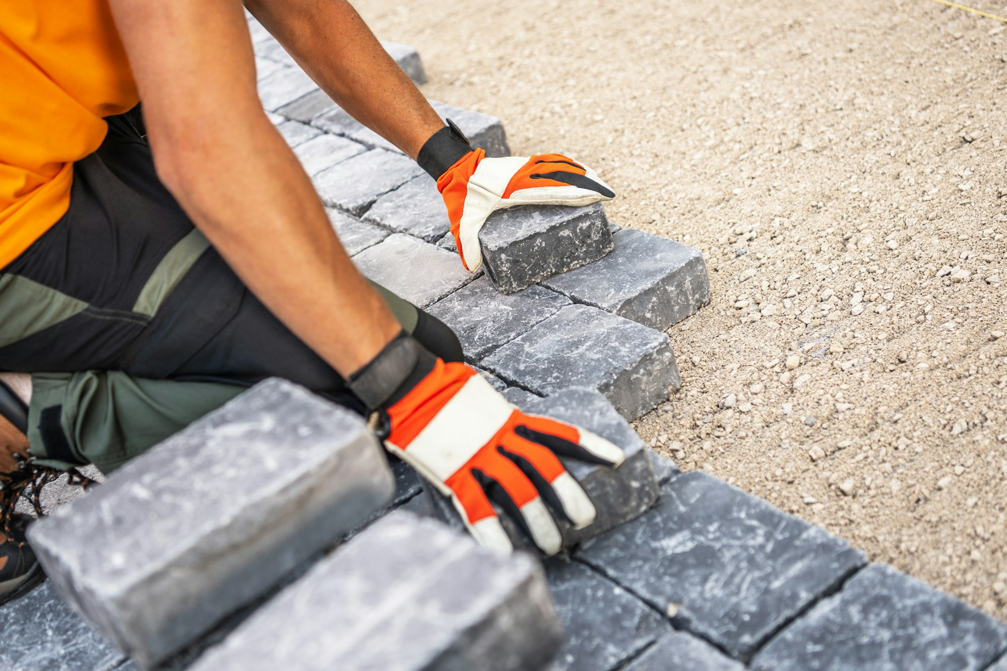 Construction Worker Laying Pavement Stones on a Gravel Surface During Daytime